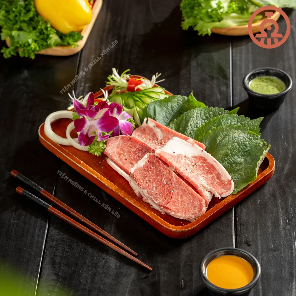 Khay ba chỉ bò nướng muối tiêu thái lát dày kèm lá tía tô, hành tây và hai chén sốt tại Tiệm Nướng & Chill Xóm Lèo