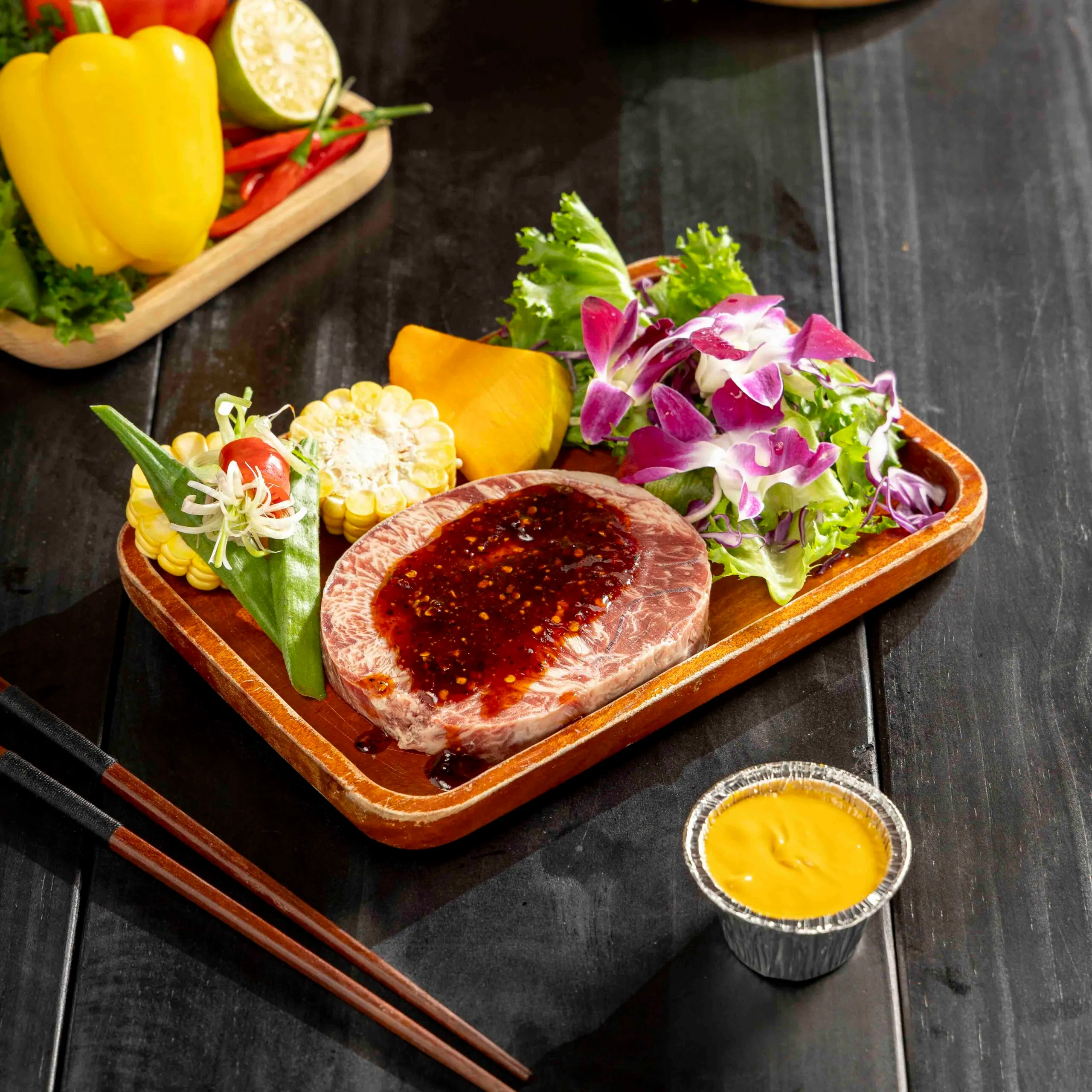 Khay bò nướng tảng phô mai trứng muối kèm bắp và rau sống trên bàn gỗ sẫm tại Tiệm Nướng & Chill Xóm Lèo