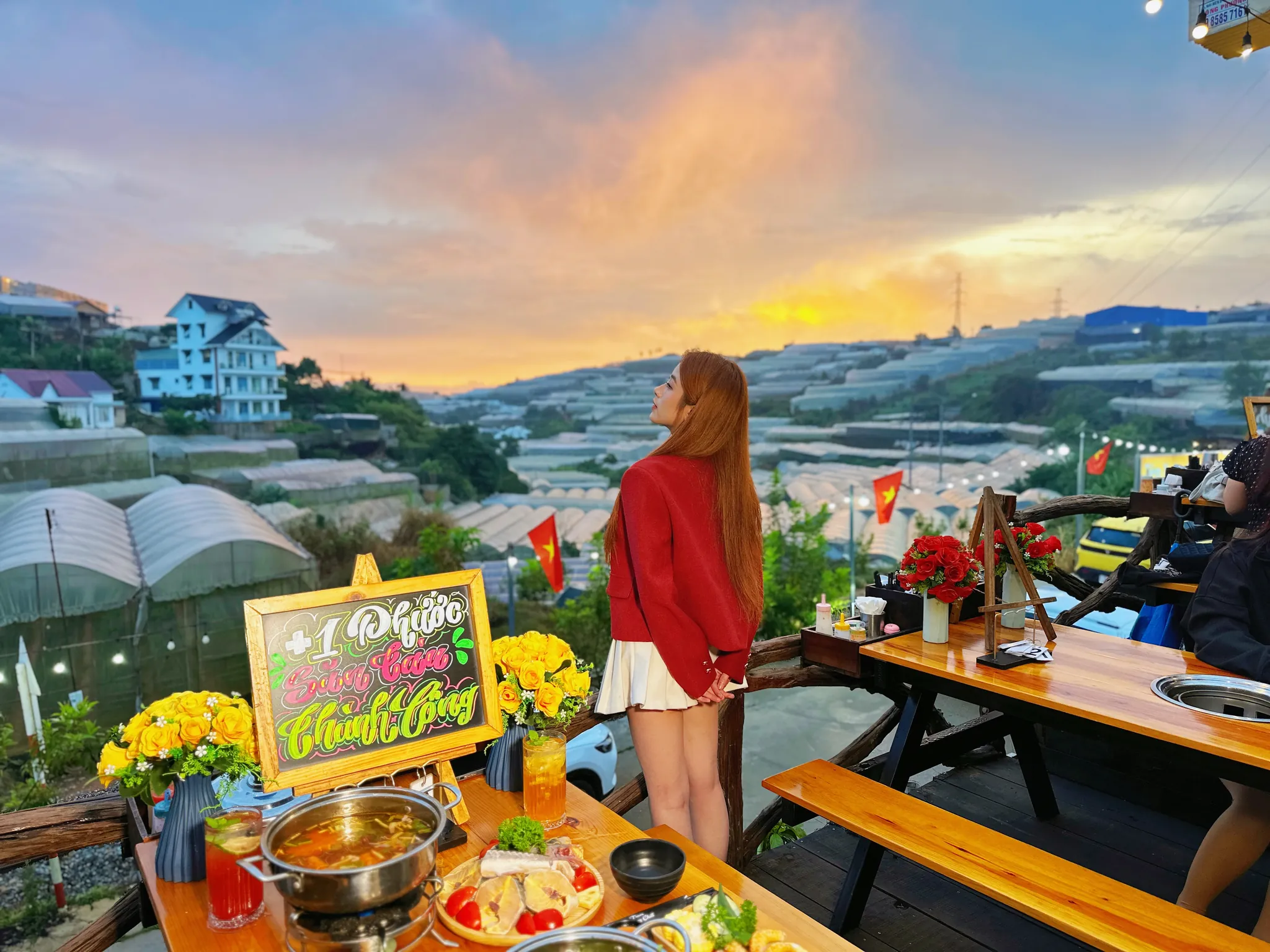 Cô gái áo đỏ ngắm hoàng hôn bên bàn lẩu nướng ở Xóm Lèo, phía sau là thung lũng nhà kính Trại Mát