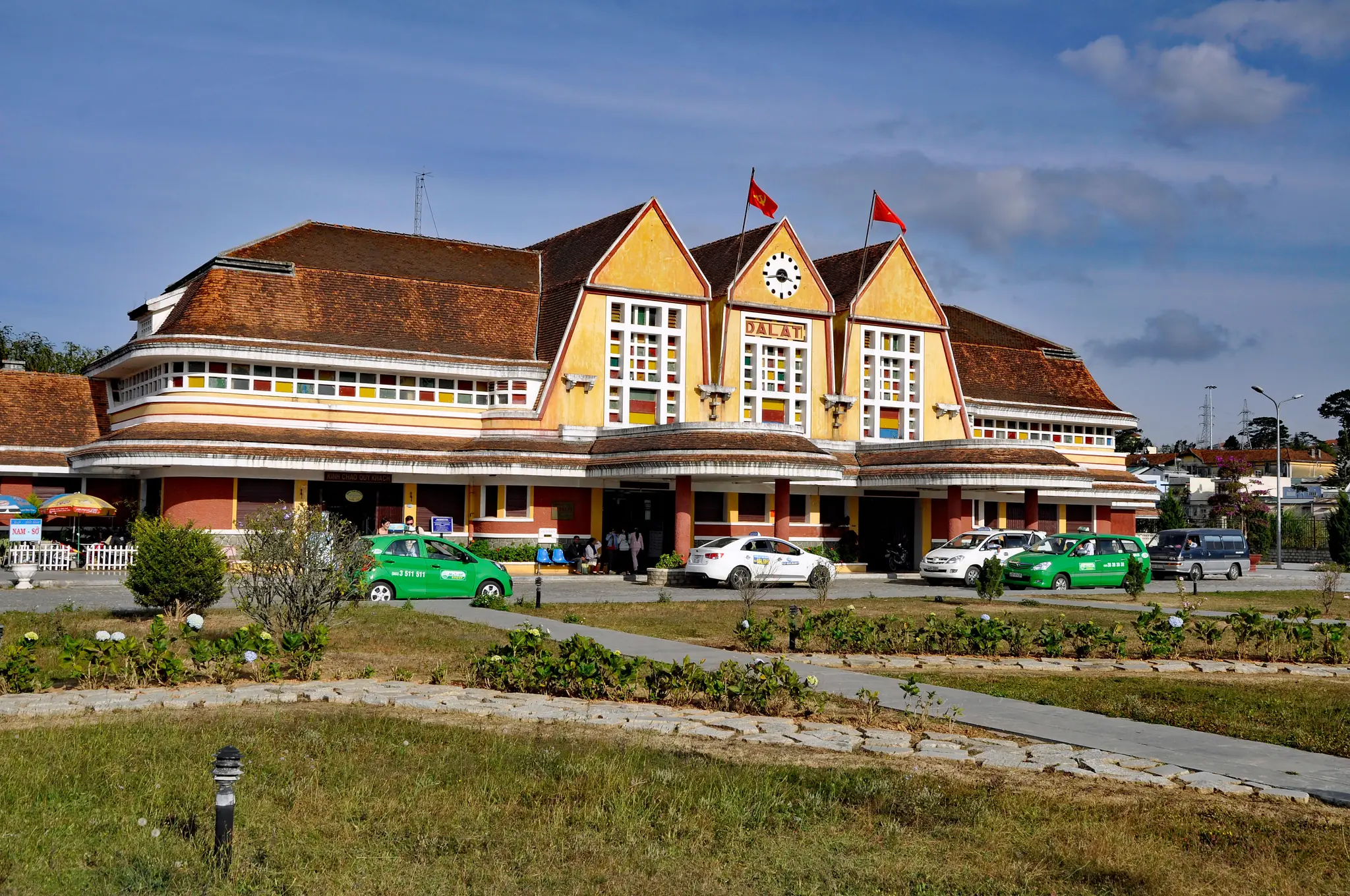 Ga Đà Lạt với ba mái nhọn và tháp đồng hồ, bãi cỏ phía trước