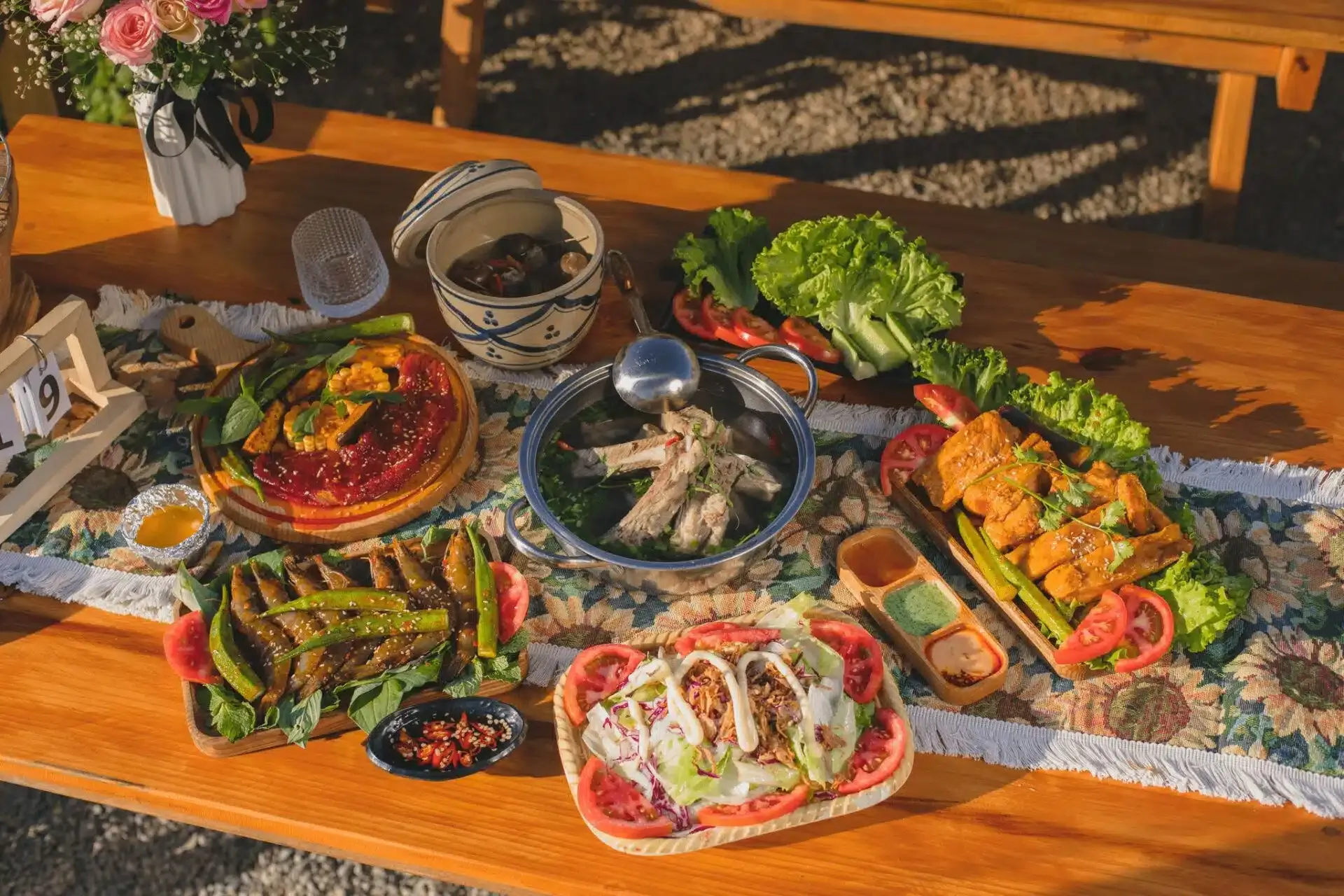 Mâm nướng Xóm Lèo bày trên bàn gỗ: thịt ướp, cá khô chiên, lẩu sườn, salad và đồ chấm